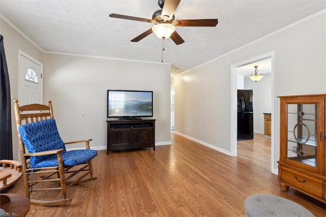 sitting room featuring a ceiling fan, crown molding, light wood-style flooring, and baseboards