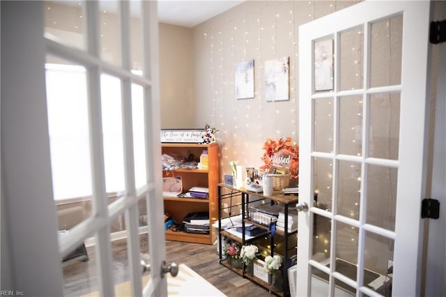 interior space featuring wallpapered walls, wood finished floors, and french doors