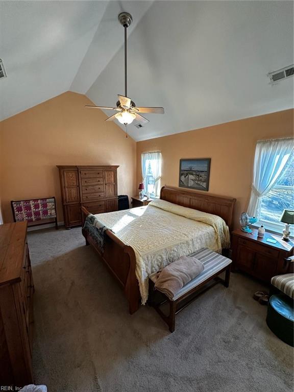 bedroom featuring lofted ceiling, visible vents, dark carpet, and ceiling fan