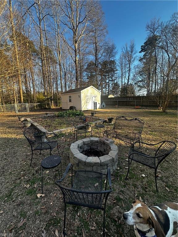 view of yard featuring an outdoor fire pit, fence, an outbuilding, and a storage shed