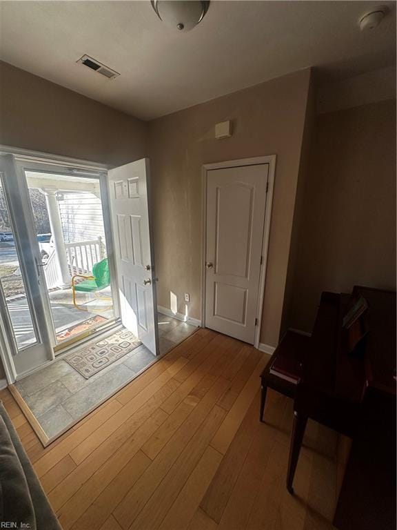 foyer entrance with wood-type flooring, visible vents, and baseboards