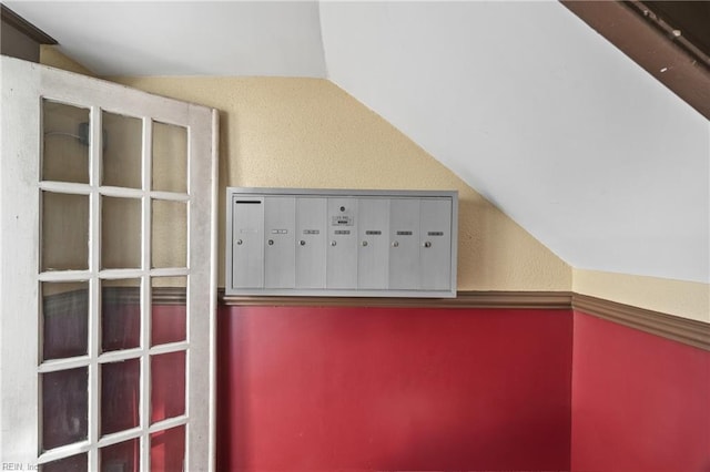 bonus room with lofted ceiling, a textured wall, and mail area