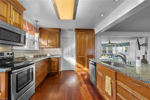 kitchen with brown cabinets, dark stone countertops, stainless steel appliances, and a sink