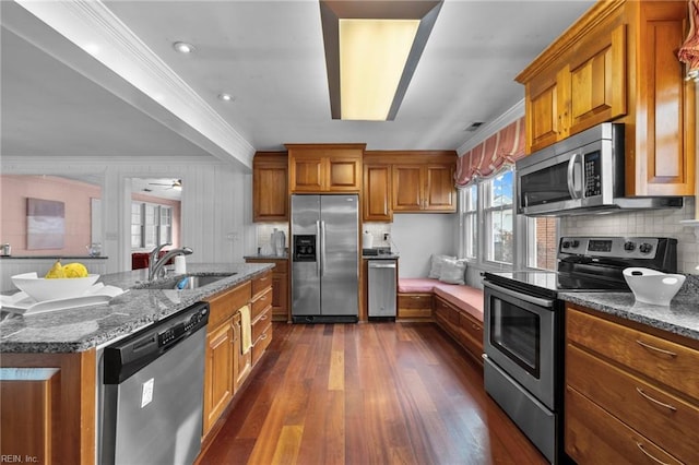 kitchen featuring stainless steel appliances, dark wood-type flooring, a sink, ornamental molding, and brown cabinets