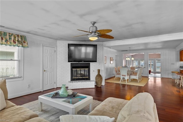 living area featuring ornamental molding, a brick fireplace, wood finished floors, and a ceiling fan