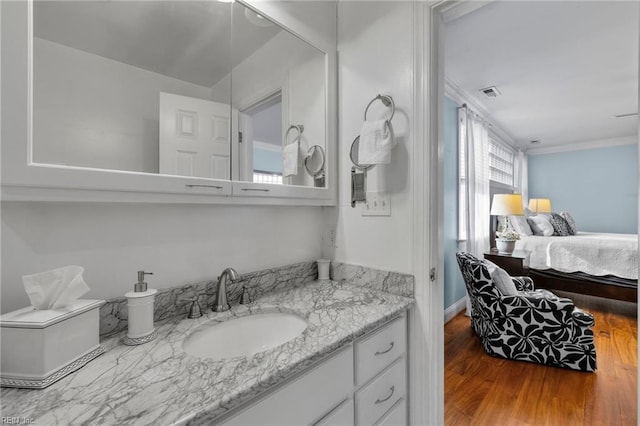 bathroom featuring crown molding, visible vents, wood finished floors, and vanity