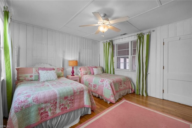 bedroom with ceiling fan, visible vents, and wood finished floors