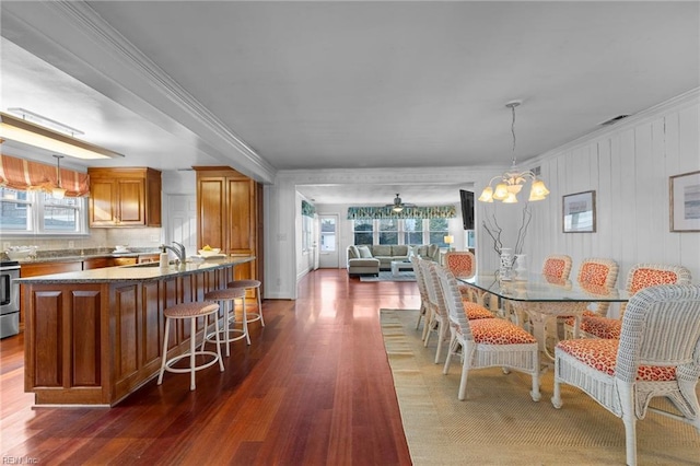 dining room featuring ceiling fan with notable chandelier, ornamental molding, dark wood finished floors, and visible vents