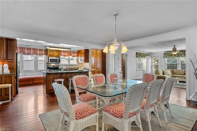 dining space featuring ornamental molding, dark wood-style flooring, and ceiling fan with notable chandelier