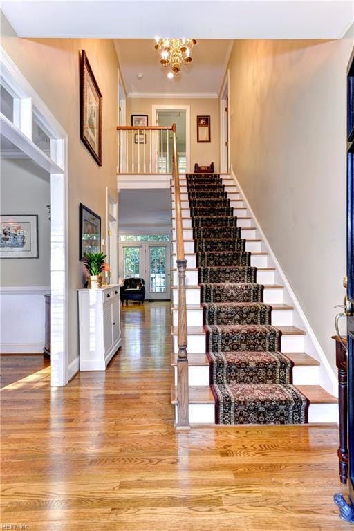 entrance foyer featuring a high ceiling, wood finished floors, baseboards, stairs, and crown molding