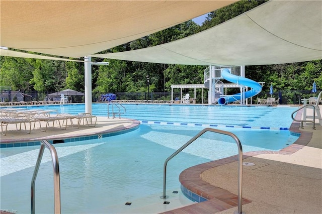 pool featuring a water slide, fence, and a patio