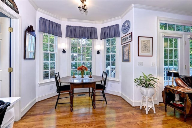 dining space featuring baseboards, light wood finished floors, and crown molding