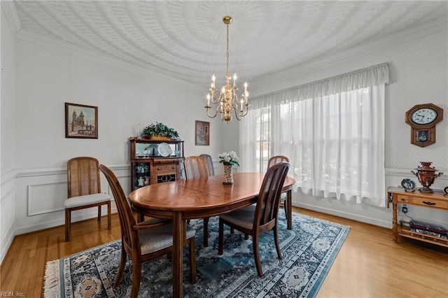 dining room featuring a chandelier, light wood-style floors, wainscoting, and crown molding