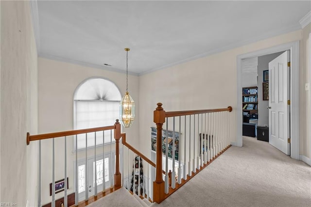 corridor with a chandelier, carpet flooring, an upstairs landing, and crown molding