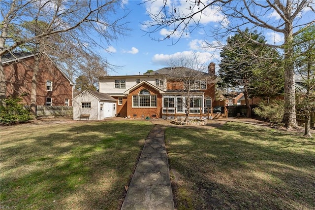 back of house featuring brick siding, a chimney, a lawn, crawl space, and fence