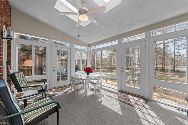 sunroom / solarium with vaulted ceiling with skylight, plenty of natural light, and a ceiling fan