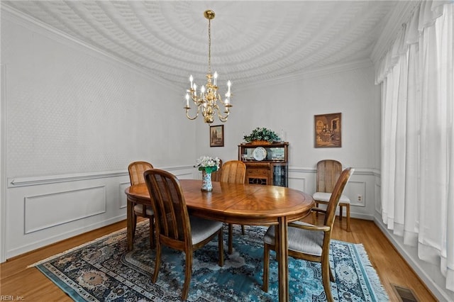 dining room with light wood finished floors, visible vents, crown molding, and an inviting chandelier