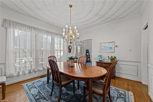 dining area featuring wallpapered walls, light wood-style flooring, crown molding, and wainscoting