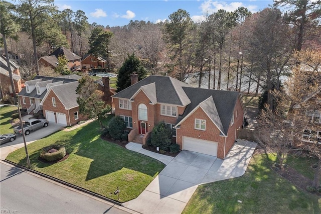 view of front of property with an attached garage, brick siding, concrete driveway, a chimney, and a front yard