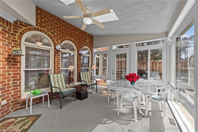 sunroom / solarium featuring lofted ceiling with skylight and ceiling fan