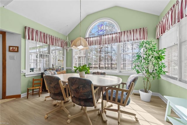 dining room featuring lofted ceiling, baseboards, and wood finished floors