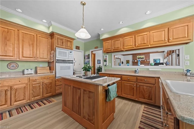 kitchen with a center island, white appliances, a sink, and light wood finished floors