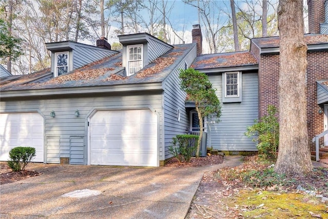 view of front of property with driveway, a chimney, and an attached garage