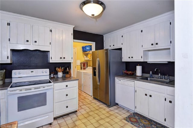 kitchen featuring separate washer and dryer, white appliances, a sink, white cabinets, and dark countertops