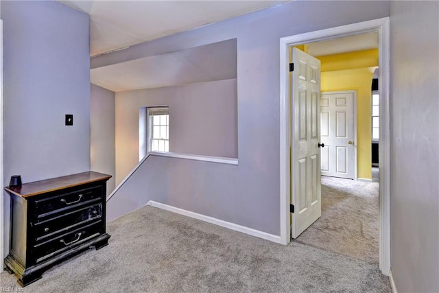 hall with baseboards, carpet flooring, and an upstairs landing