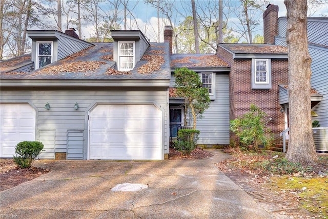 view of front facade featuring driveway, a chimney, and an attached garage