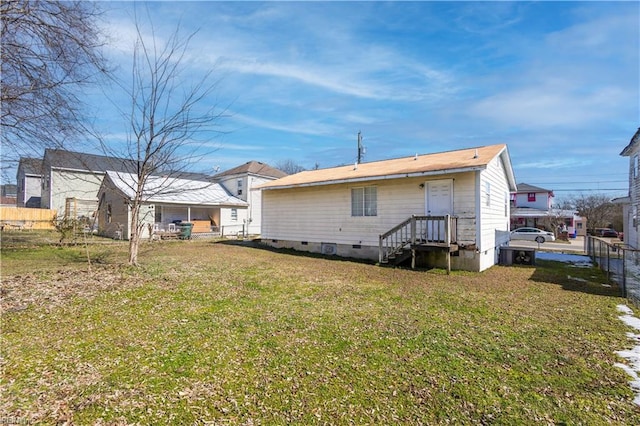 rear view of house with crawl space, fence, and a lawn