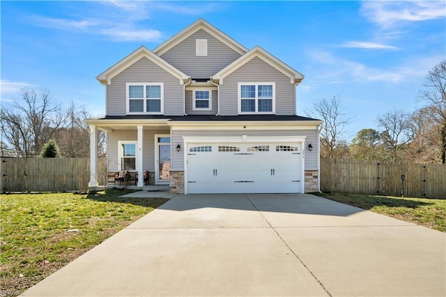 view of front of house featuring driveway, stone siding, fence, and a porch