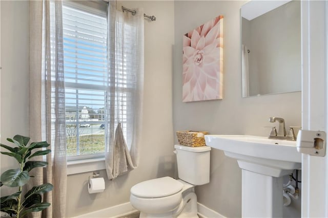 half bath featuring a sink, toilet, and baseboards