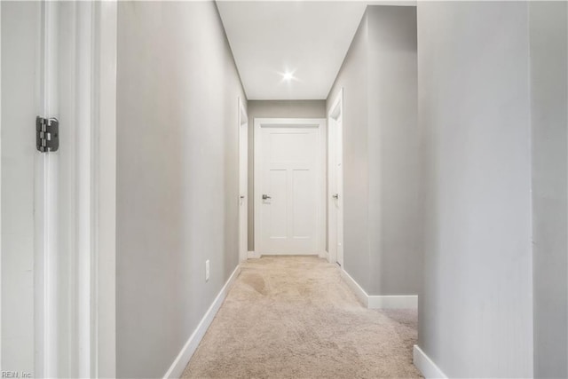 hallway featuring baseboards and light colored carpet