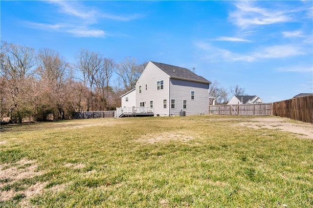 back of property with a deck, a yard, central AC, and a fenced backyard