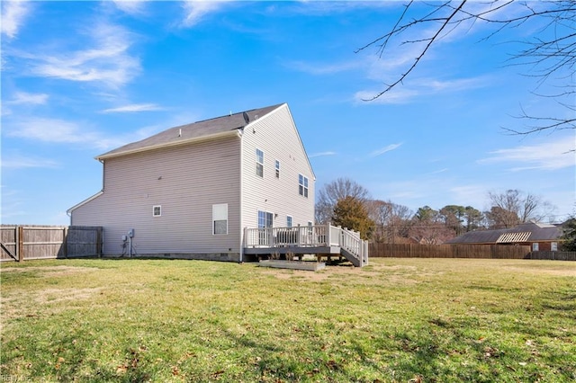 back of property with a fenced backyard, a lawn, and a wooden deck