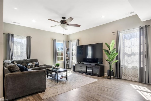 living area with ceiling fan, wood finished floors, and visible vents