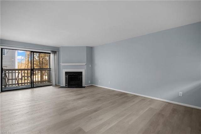 unfurnished living room featuring light wood-style flooring, baseboards, and a fireplace with flush hearth