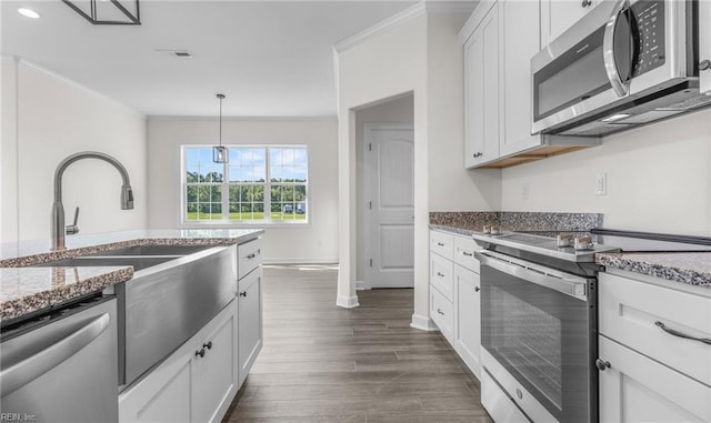 kitchen featuring appliances with stainless steel finishes, decorative light fixtures, light stone countertops, crown molding, and white cabinetry