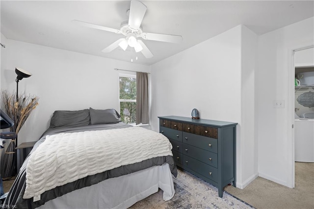 bedroom with a ceiling fan, washer / clothes dryer, light carpet, and baseboards