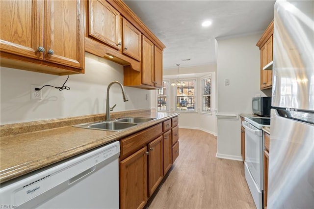 kitchen with crown molding, light countertops, light wood-style floors, a sink, and white appliances