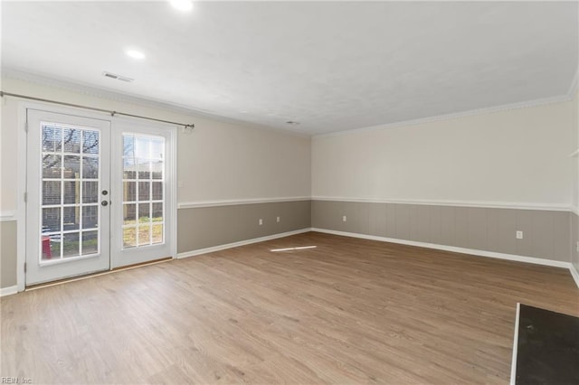 spare room featuring french doors, crown molding, visible vents, wainscoting, and wood finished floors