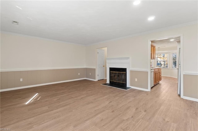 unfurnished living room featuring ornamental molding, a glass covered fireplace, and light wood-style flooring