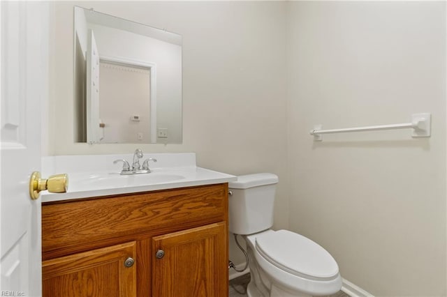 bathroom with toilet, vanity, and baseboards