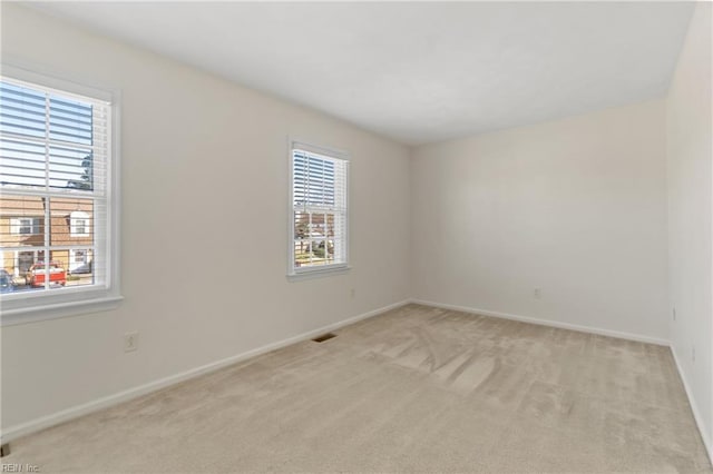 spare room with light carpet, visible vents, and baseboards