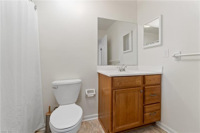 bathroom with baseboards, vanity, and toilet