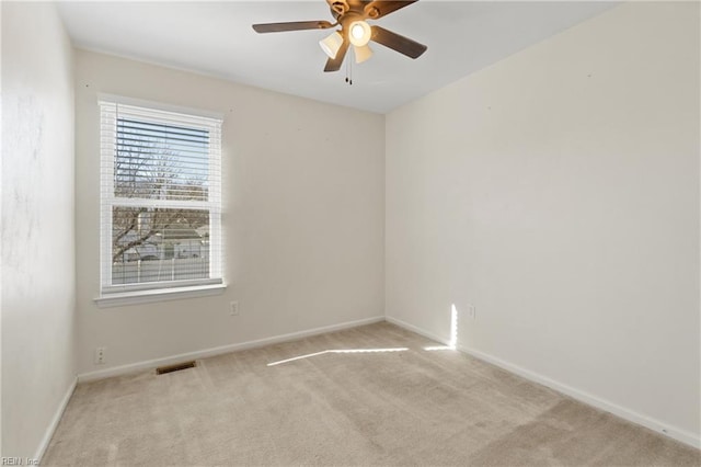 empty room with light colored carpet, visible vents, ceiling fan, and baseboards