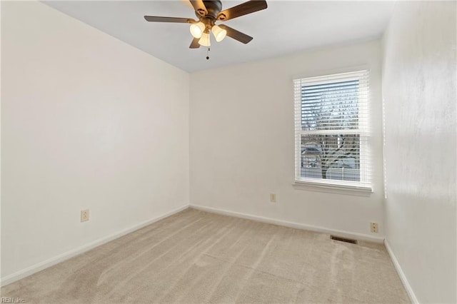 unfurnished room with a ceiling fan, light colored carpet, visible vents, and baseboards