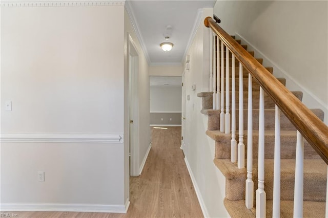 stairway with baseboards, wood finished floors, and crown molding