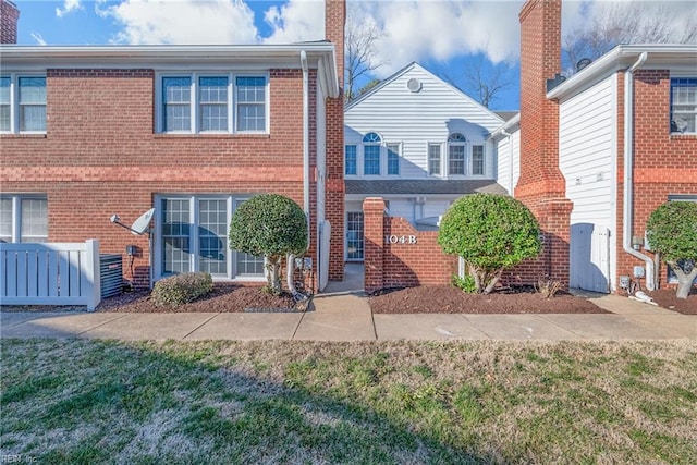 view of front of house with brick siding, a chimney, and a front lawn